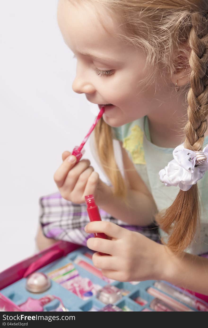 Portrait of a little caucasian fashionable girl using decorative cosmetics indoors