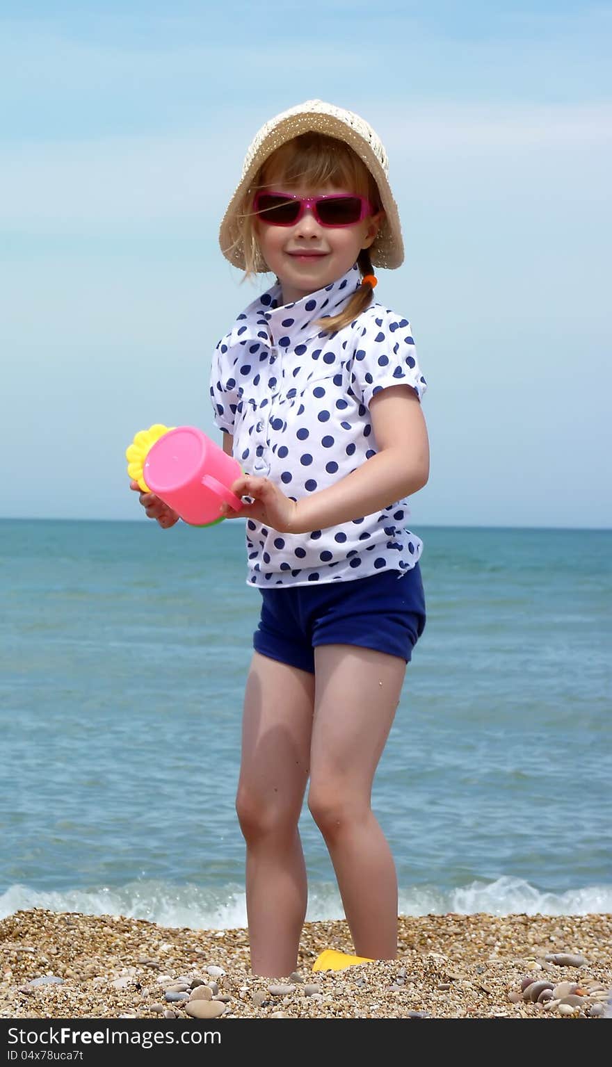 The smiling girl in sunglasses with a toy on the background of the sea. The smiling girl in sunglasses with a toy on the background of the sea