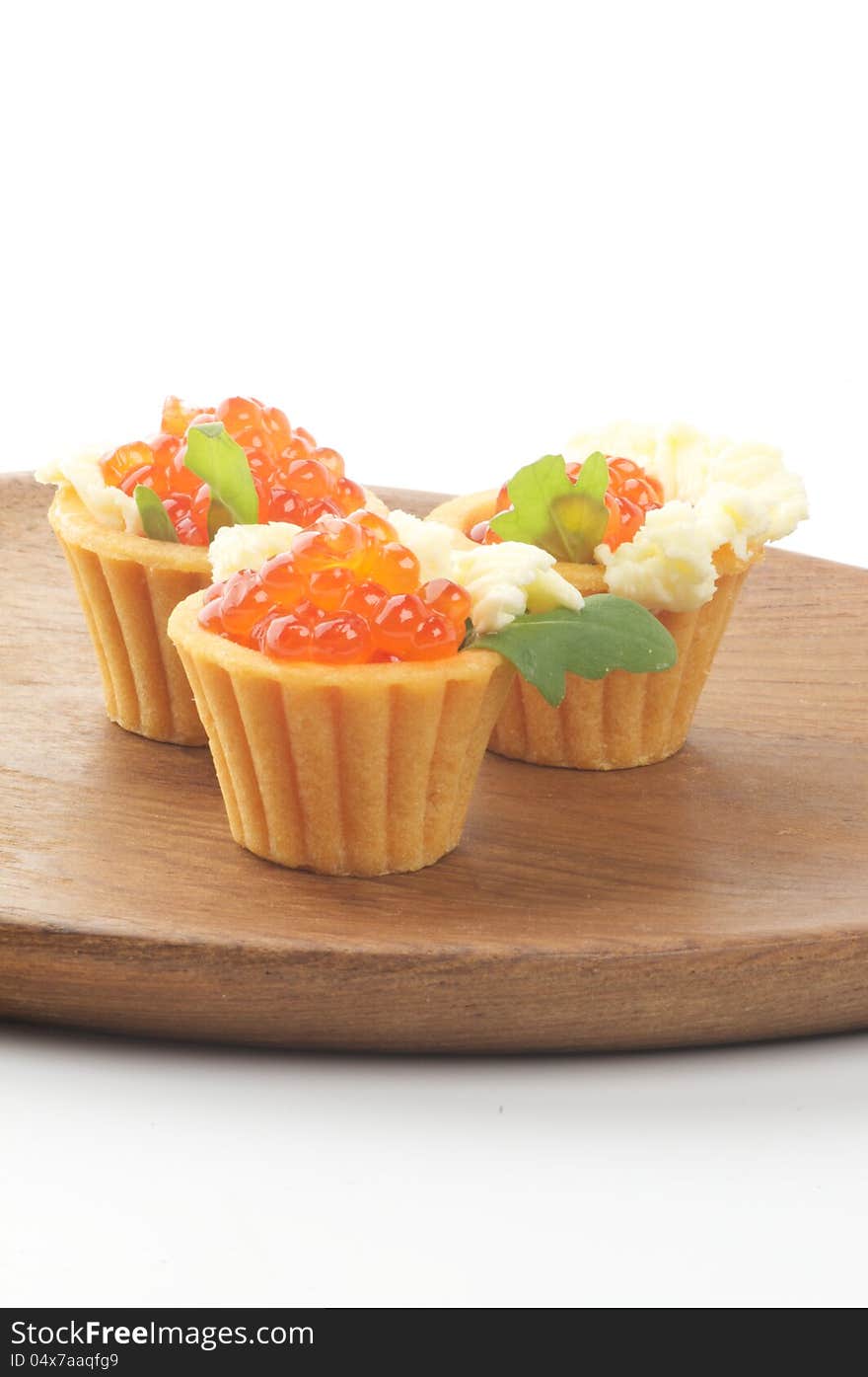 Tartlets with Perfect Red Caviar, Greens and Butter on Wooden Plate closeup. Tartlets with Perfect Red Caviar, Greens and Butter on Wooden Plate closeup