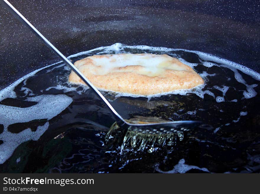 Donut floating in hot oil in skillet. Donut floating in hot oil in skillet