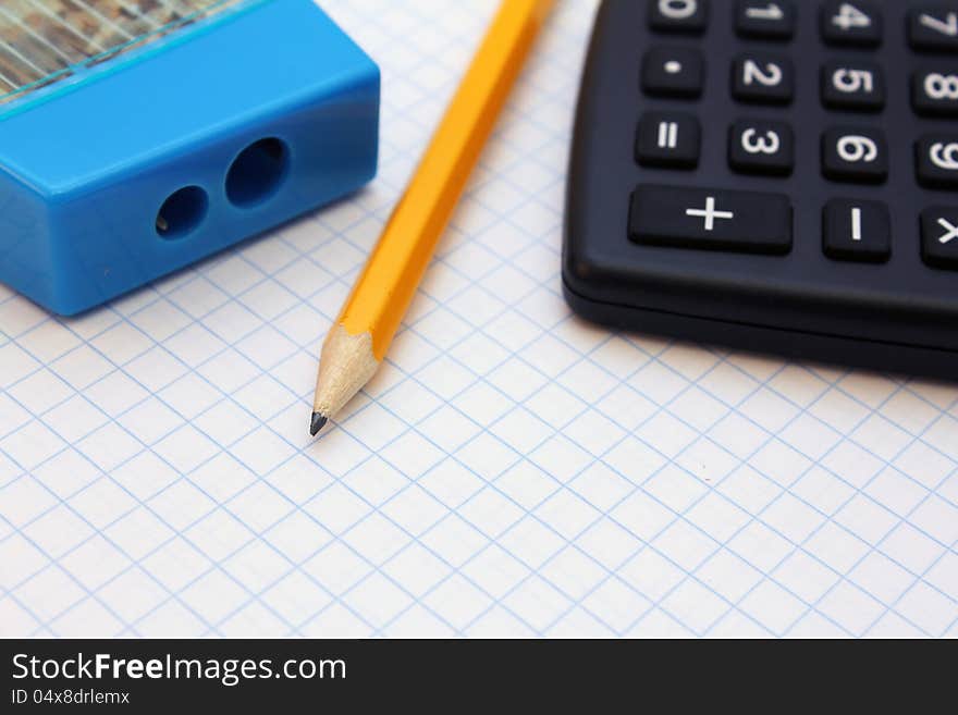 Pencil, sharpener and calculator on graph paper. Pencil, sharpener and calculator on graph paper