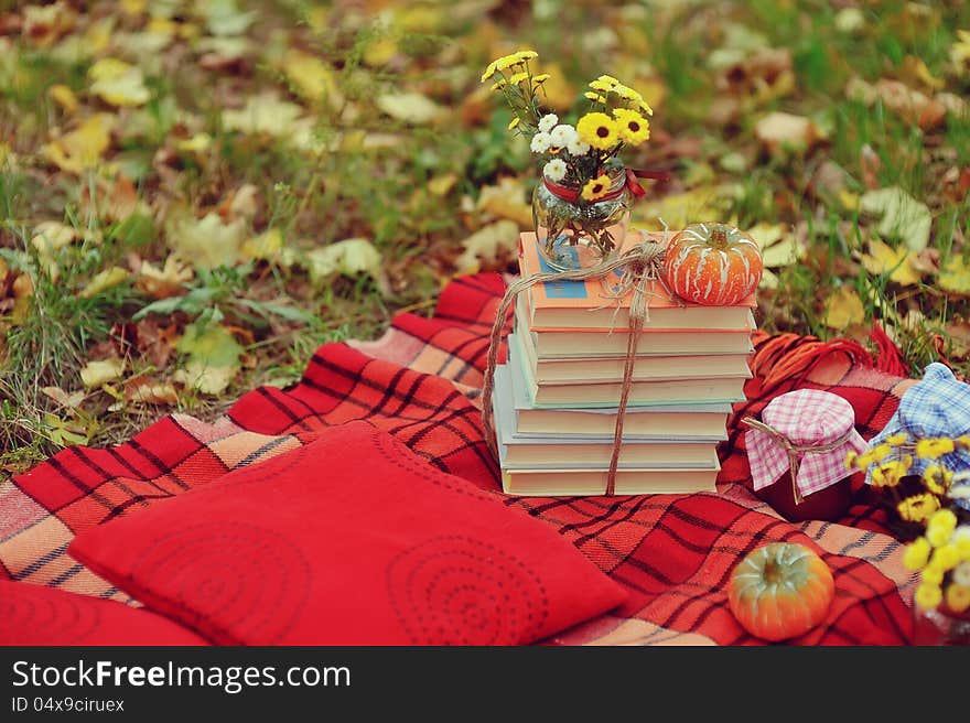 Outdoors ripe pumpkin and a stack of books with a bouquet of autumn flowers. Outdoors ripe pumpkin and a stack of books with a bouquet of autumn flowers