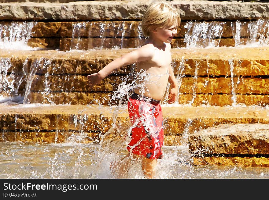 Young boy playing in water fountain