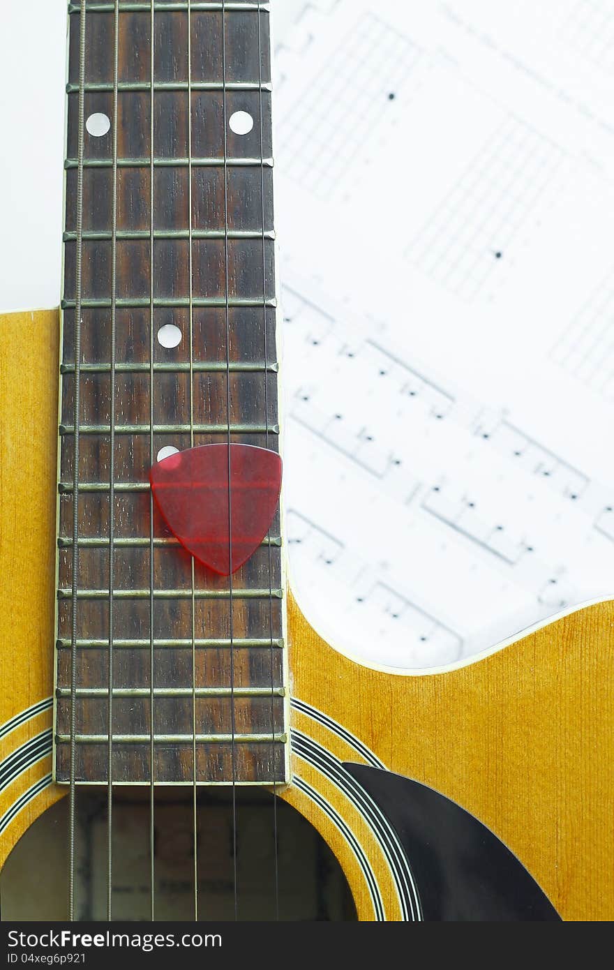 Acoustic Guitar on music note sheet ,focus at the Guitar, blur at music note sheet.