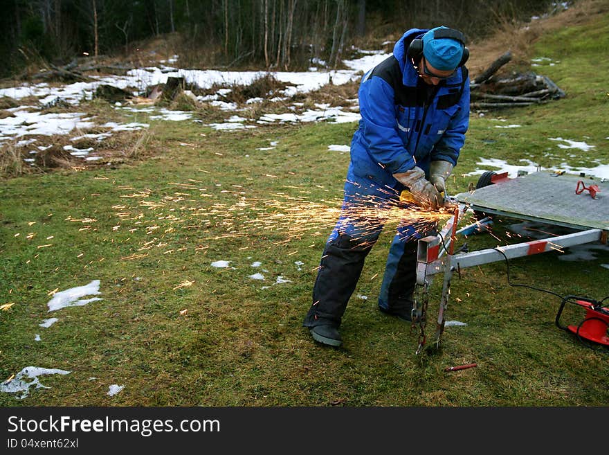 Man working outside grinding steel on a trailer