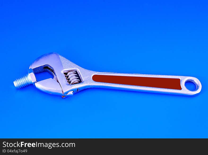 Wrench with adjustable bolt photographed against a blue background. Wrench with adjustable bolt photographed against a blue background