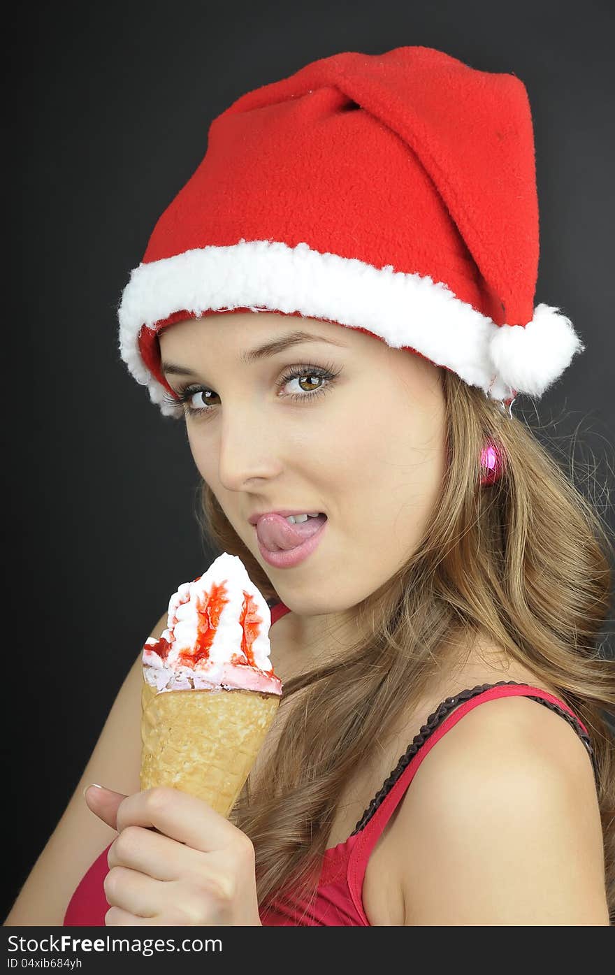 Christmas funny girl with ice cream wearing Santa hat.