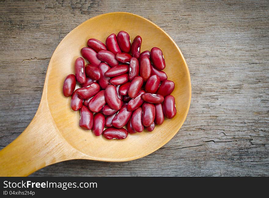 Wooden spoon with some red beans .