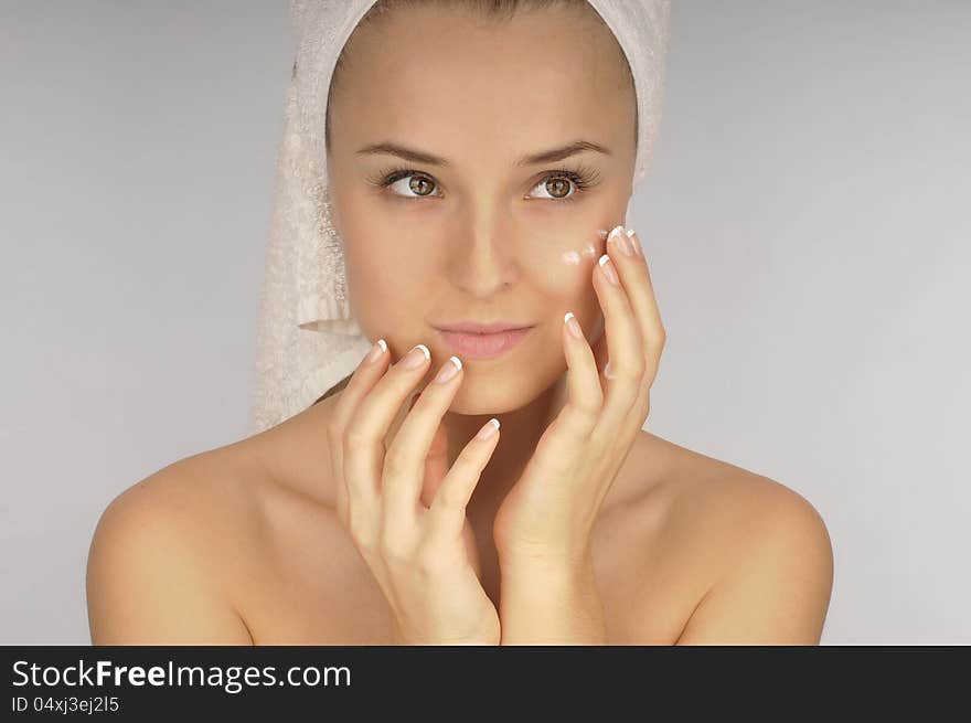 Beautiful woman applying  cream on face.