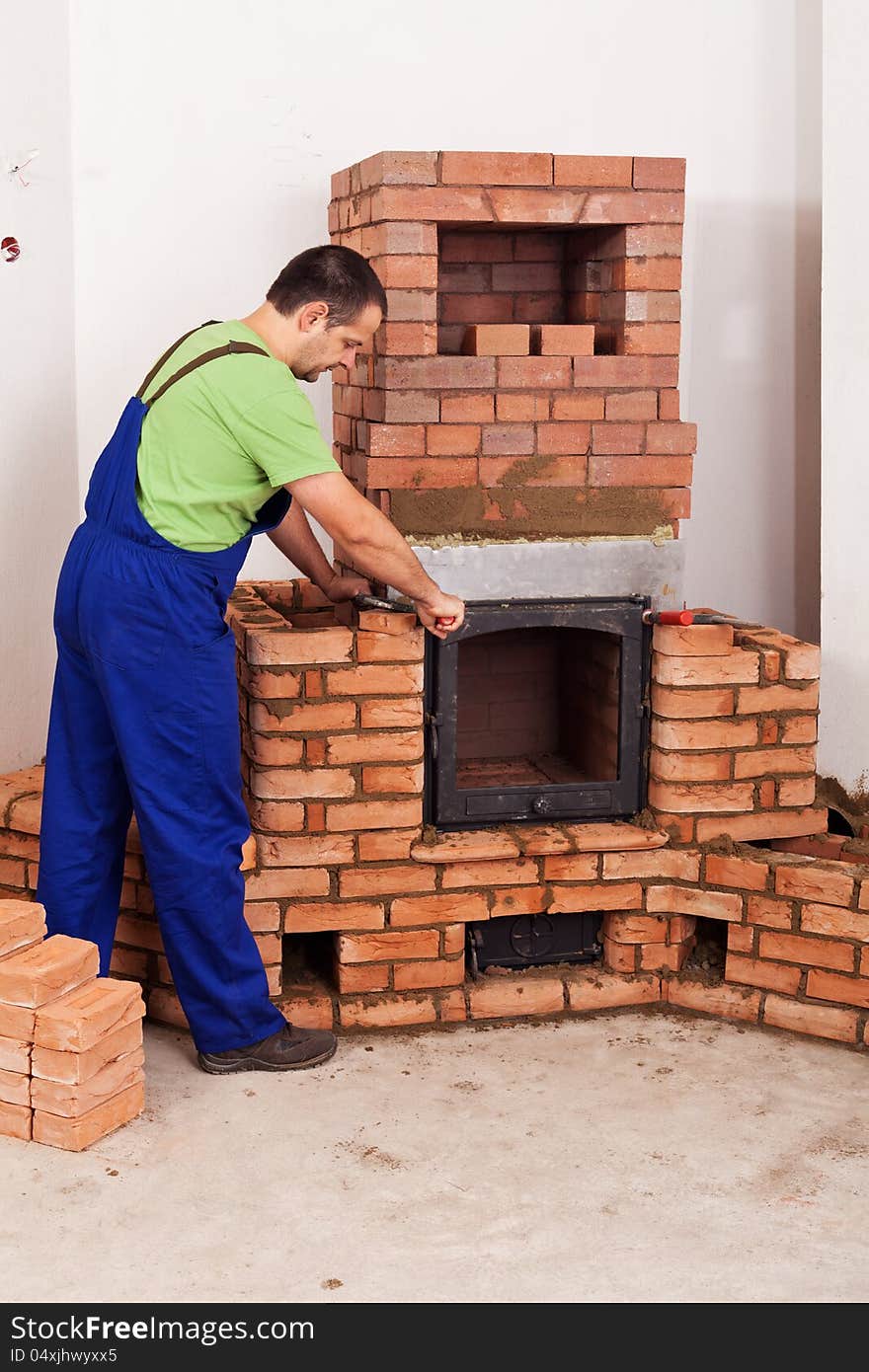 Worker mounting door to a masonry heater - half finished