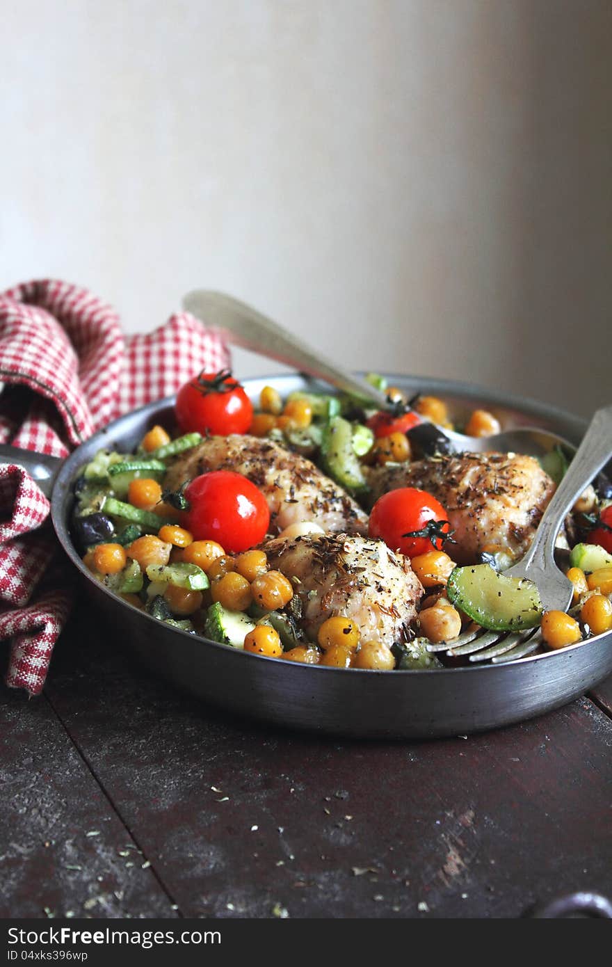 Roasted chicken with cherry tomatoes, courgette, eggplant and chickpea in a pan. Roasted chicken with cherry tomatoes, courgette, eggplant and chickpea in a pan