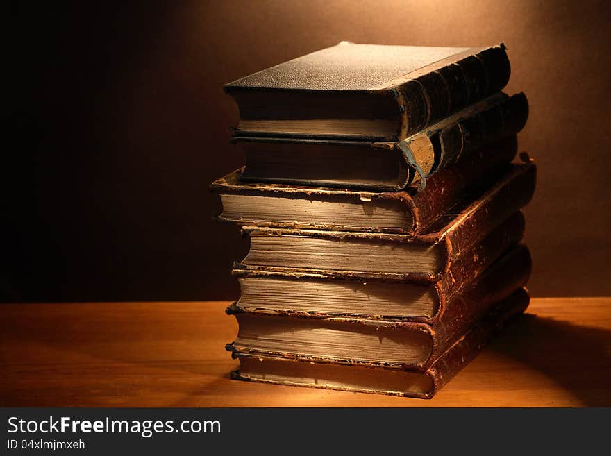 Stack of antique books on wooden surface under beam of light. Stack of antique books on wooden surface under beam of light