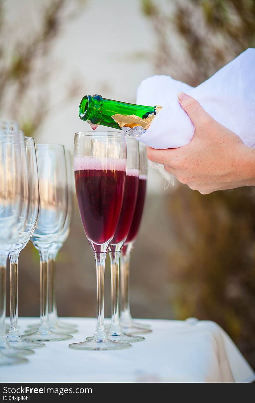 The waiter pours champagne into a glass. The waiter pours champagne into a glass