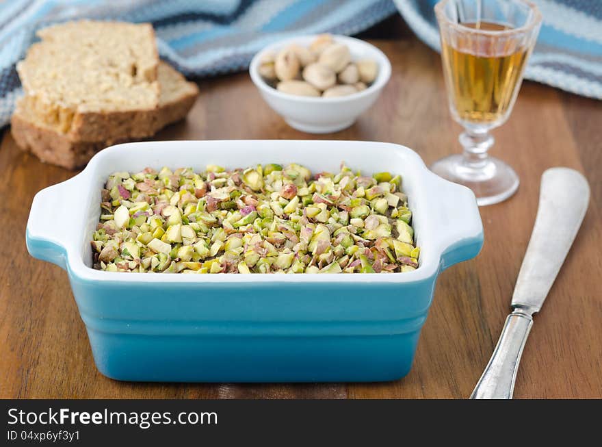 Chicken liver pate with pistachios. Bread, port wine and pistachios in the background.