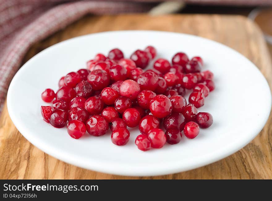 Cowberry on a white plate, selective focus