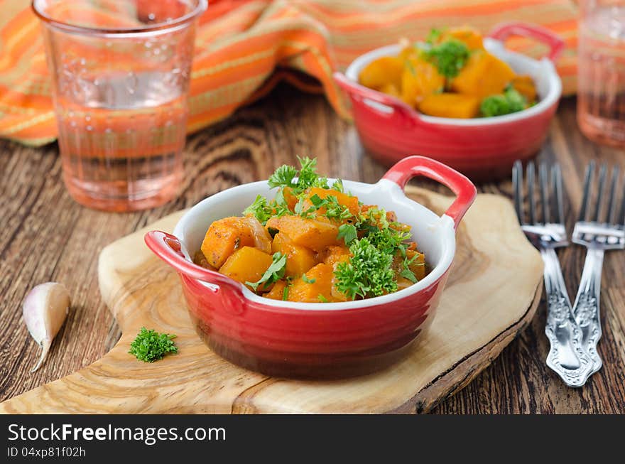 Pumpkin baked in a tomato sauce with garlic and herbs on a wooden board