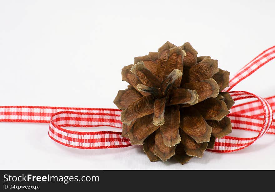 One single pine-cone decoration with red and white ribbon