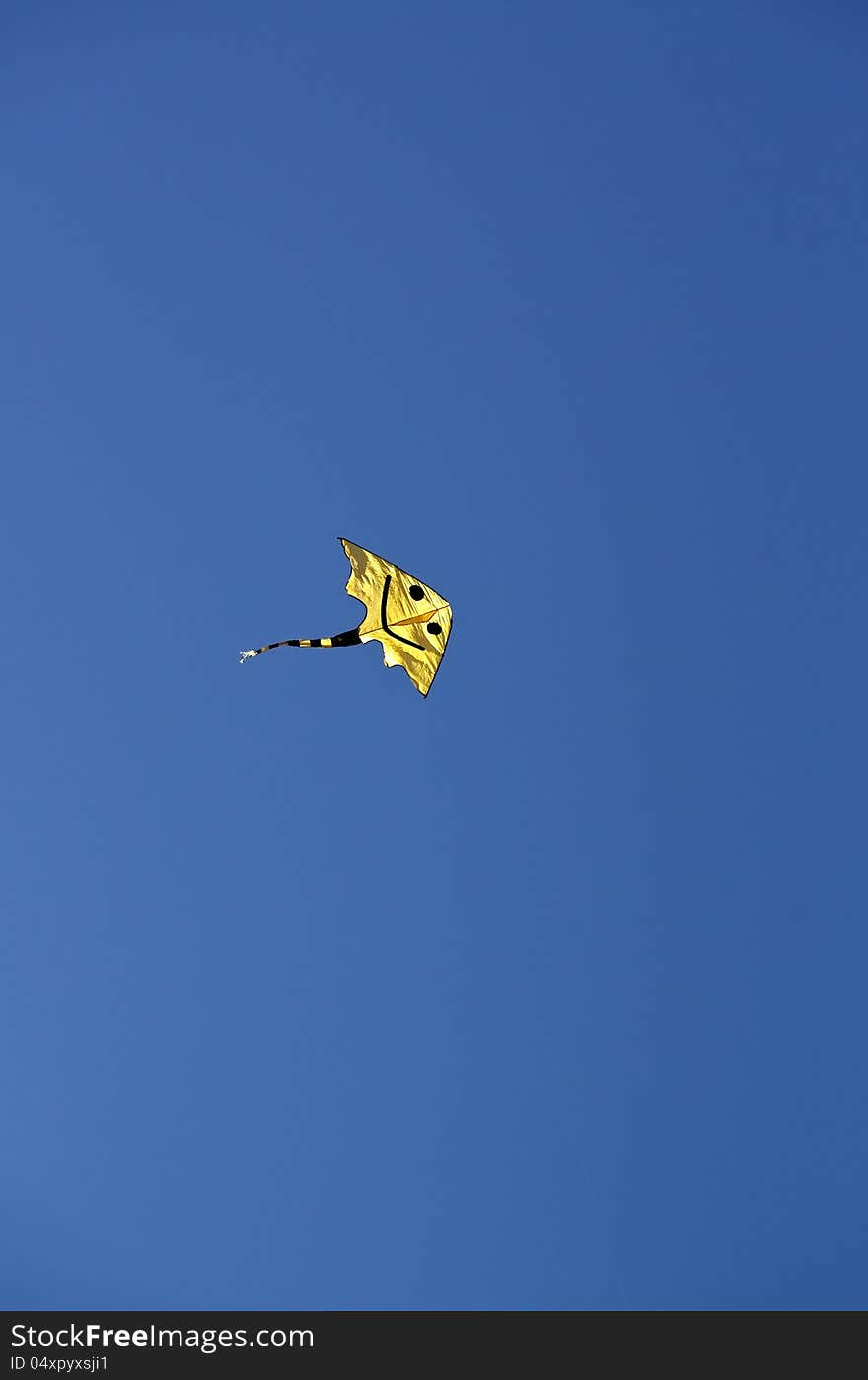 Smiling yellow kite in a cloudless sky. Smiling yellow kite in a cloudless sky