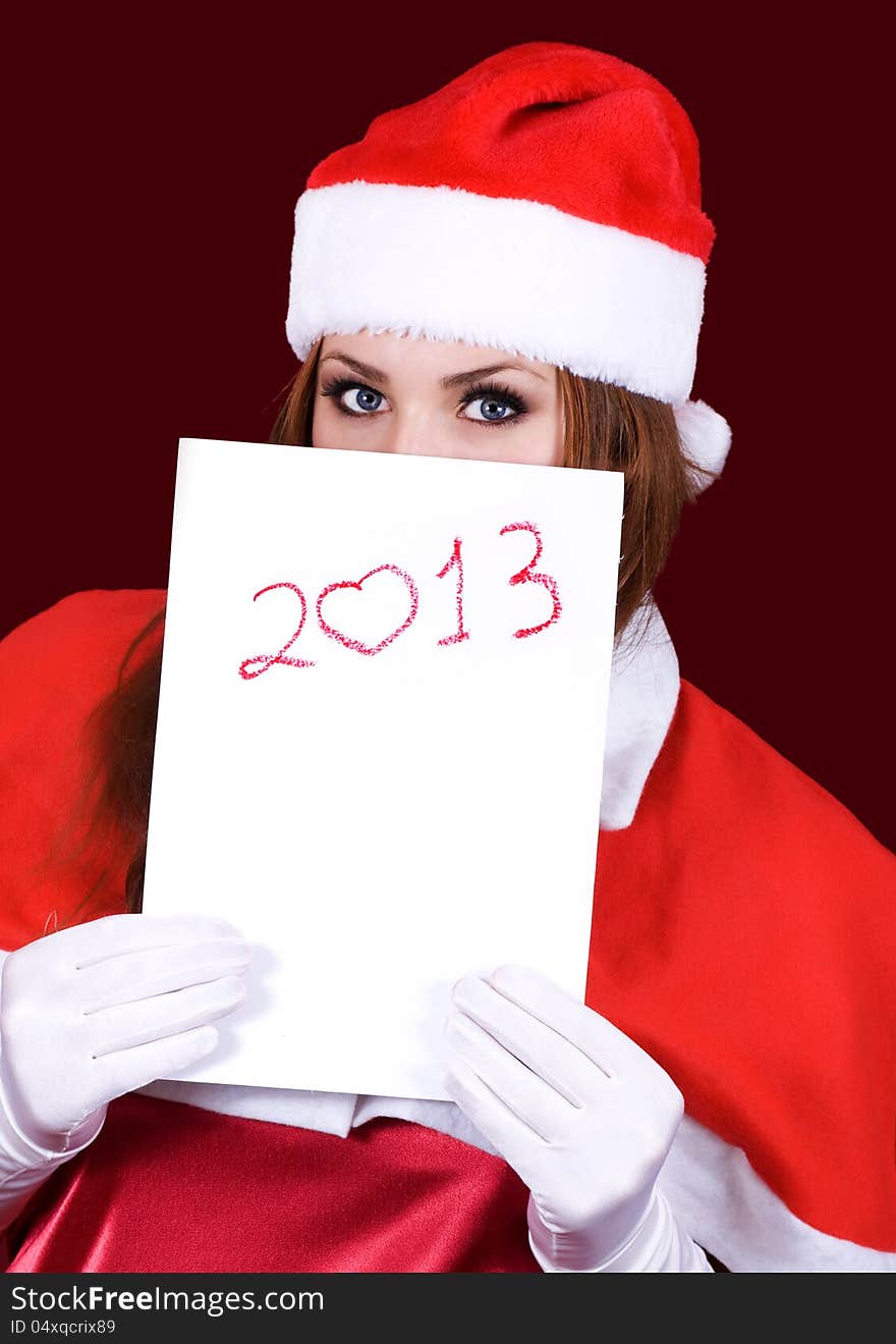 Girl in Santa's hat holding a sheet of paper with the inscription 2013. Girl in Santa's hat holding a sheet of paper with the inscription 2013