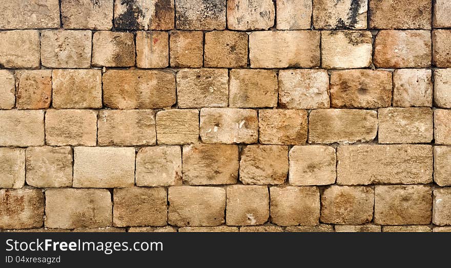 A wall made up of tiled rectangular blocks of sand stone. A wall made up of tiled rectangular blocks of sand stone