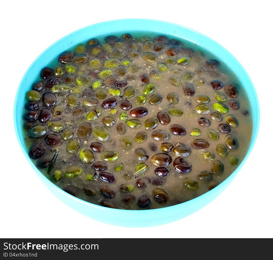 Olives being pickled with salt and water in a blue plastic container. Olives being pickled with salt and water in a blue plastic container