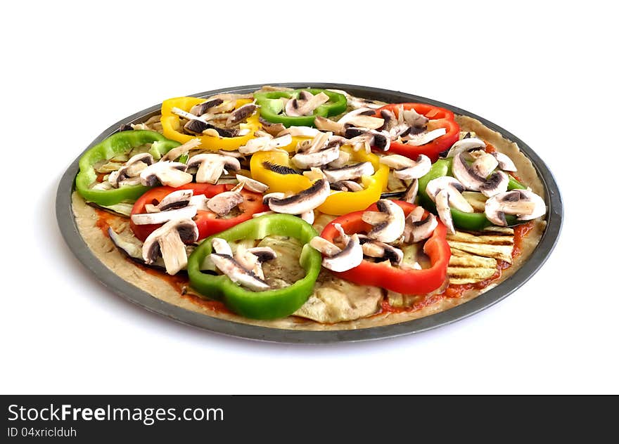 An uncooked vegetarian pizza with eggplant and zucchini slices with colorful capsicums and mushrooms. An uncooked vegetarian pizza with eggplant and zucchini slices with colorful capsicums and mushrooms