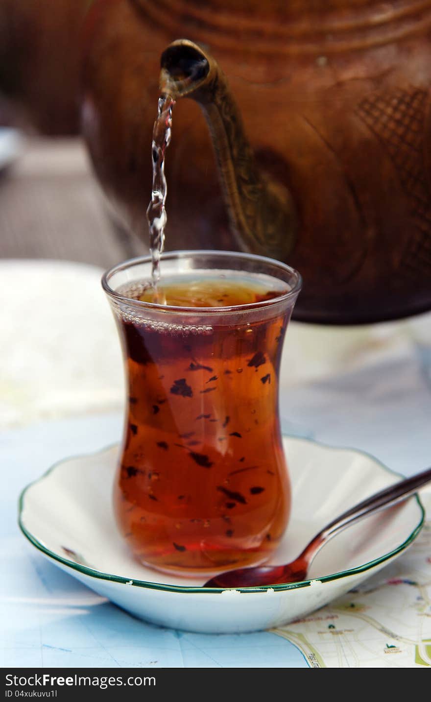 A glass of Turkish tea with tea pot