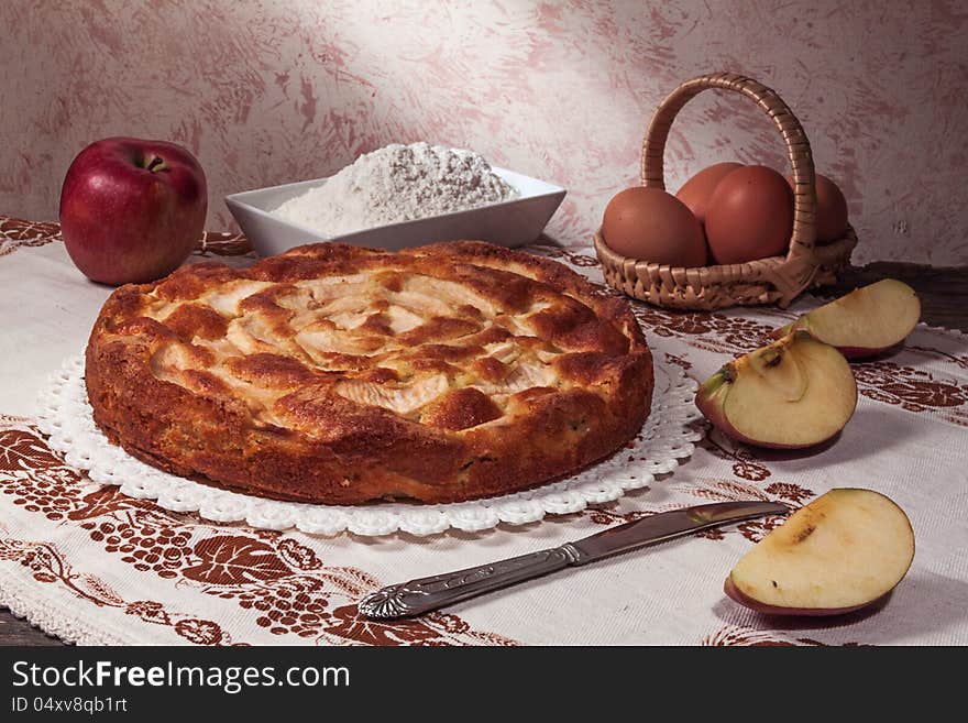 Homemade apple pie surrounded by fresh apples