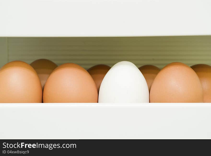 Fragment of refrigerator container full of red eggs with white one. Fragment of refrigerator container full of red eggs with white one