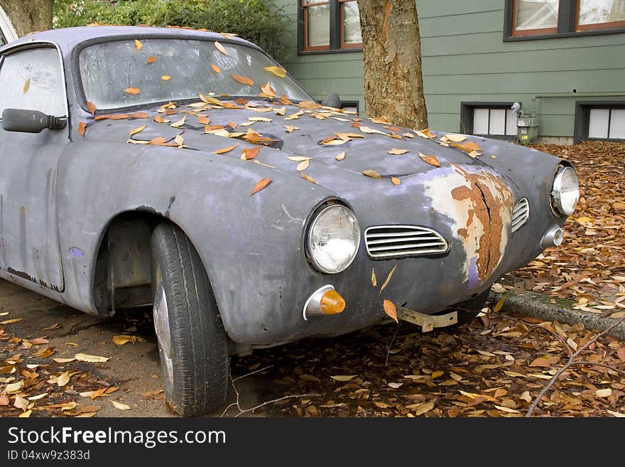 An old and rusty sport car with falling leaves. An old and rusty sport car with falling leaves.