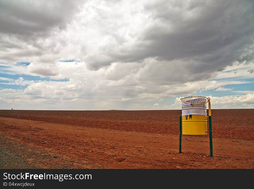 A simple low level landscape view of a red stony desert with a threatening looking sky in the background.