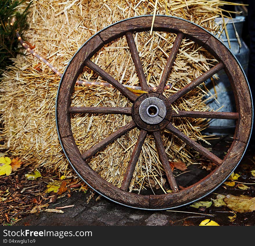 Old cartwheel standing beside hay stack