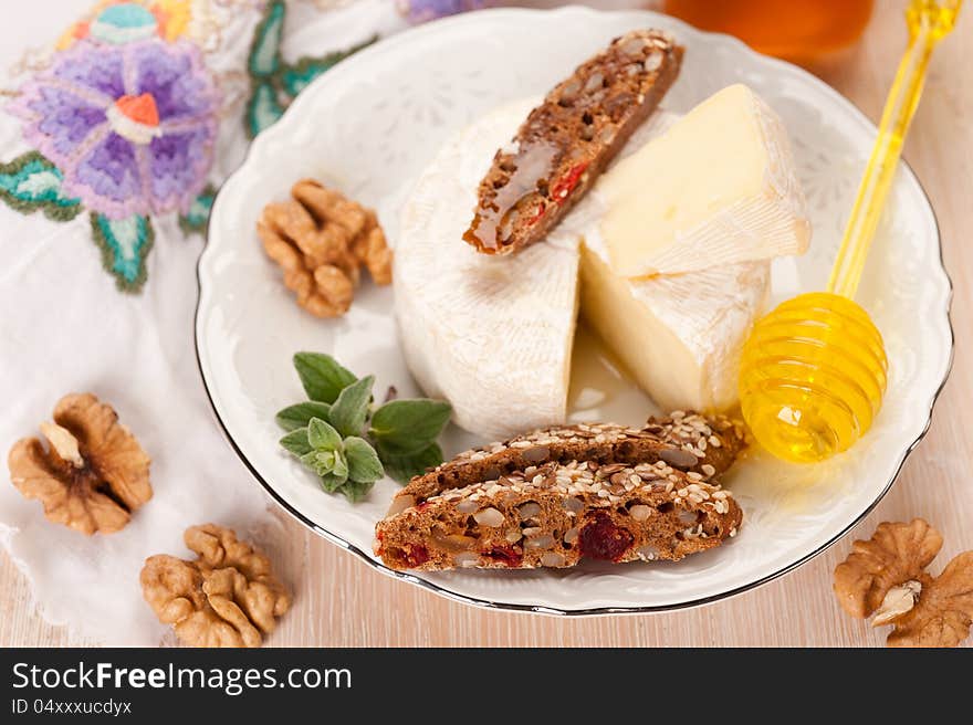 Plate with Camembert cheese, honey, nuts, and whole grain bread. Plate with Camembert cheese, honey, nuts, and whole grain bread