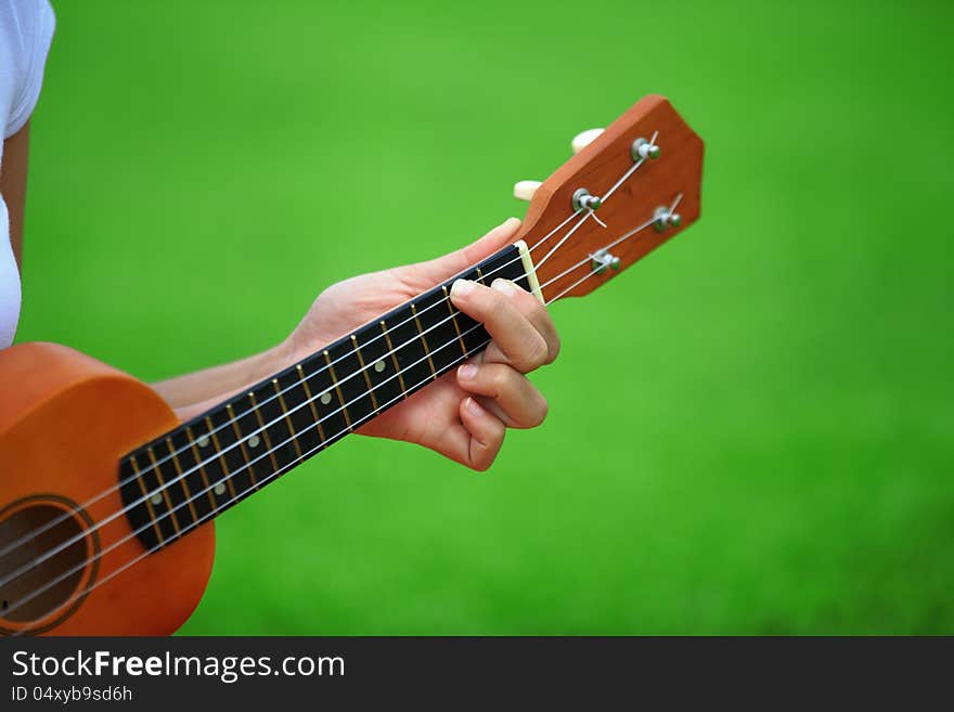 Hand and ukulele with green background