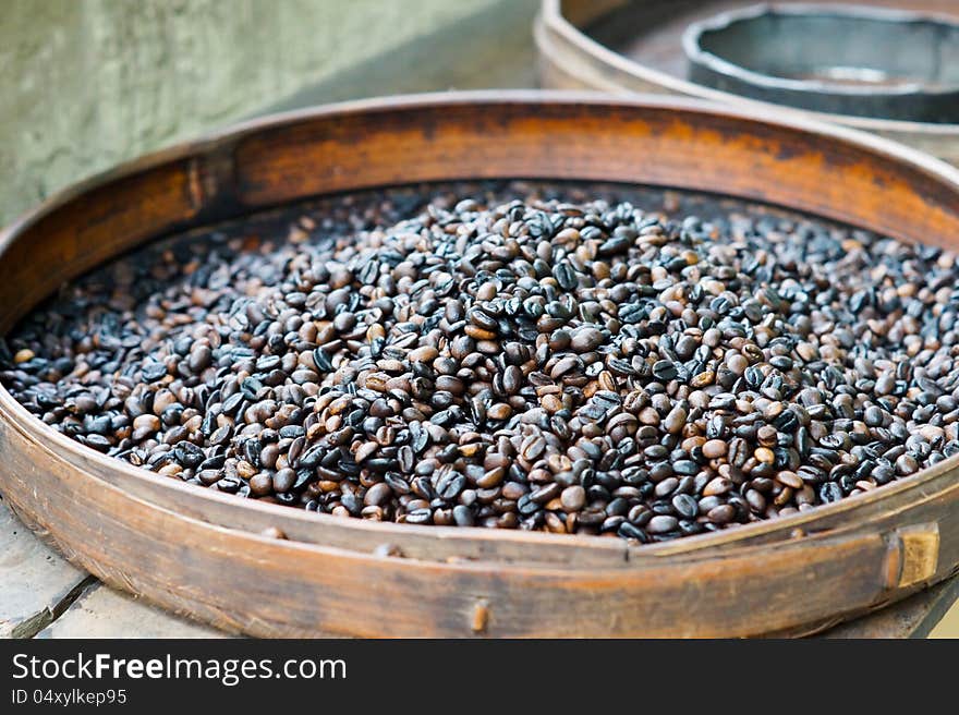 Fresh roasted coffee beans for sale in a flat round container at an outdoor market