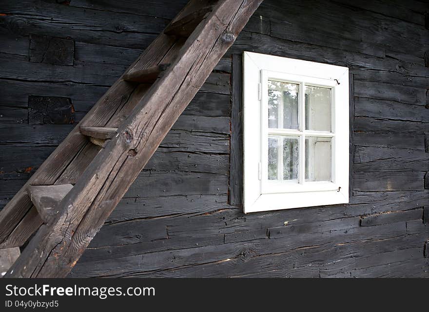 Facade of the frame house with window and ladder to the attic. Facade of the frame house with window and ladder to the attic