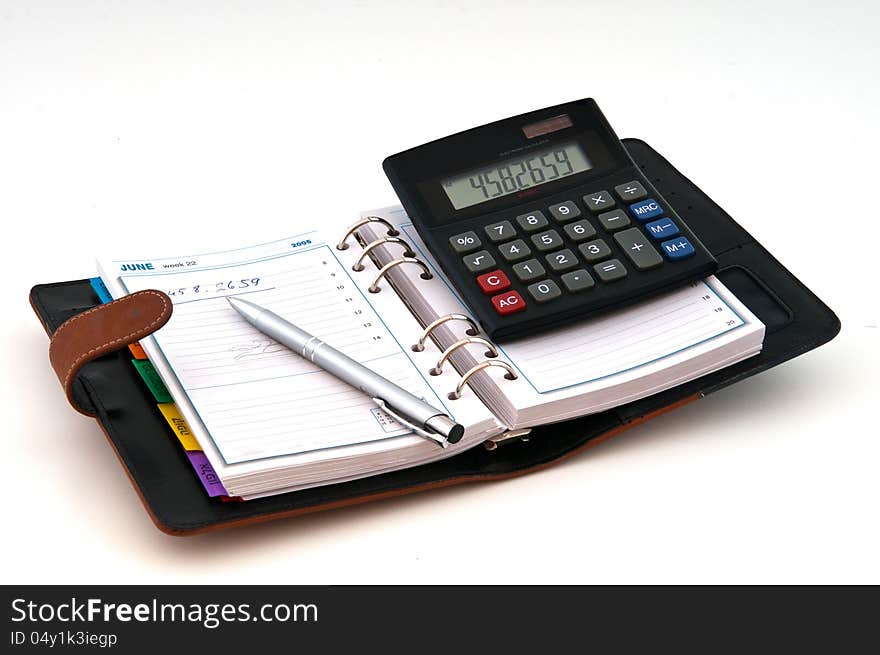 Open diary pen and calculator photographed against a white background