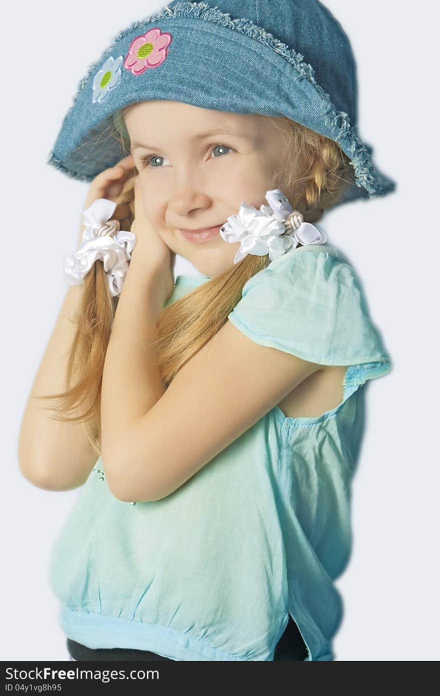 Portrait of a cute little girl in hat smiling standing with lifted hands