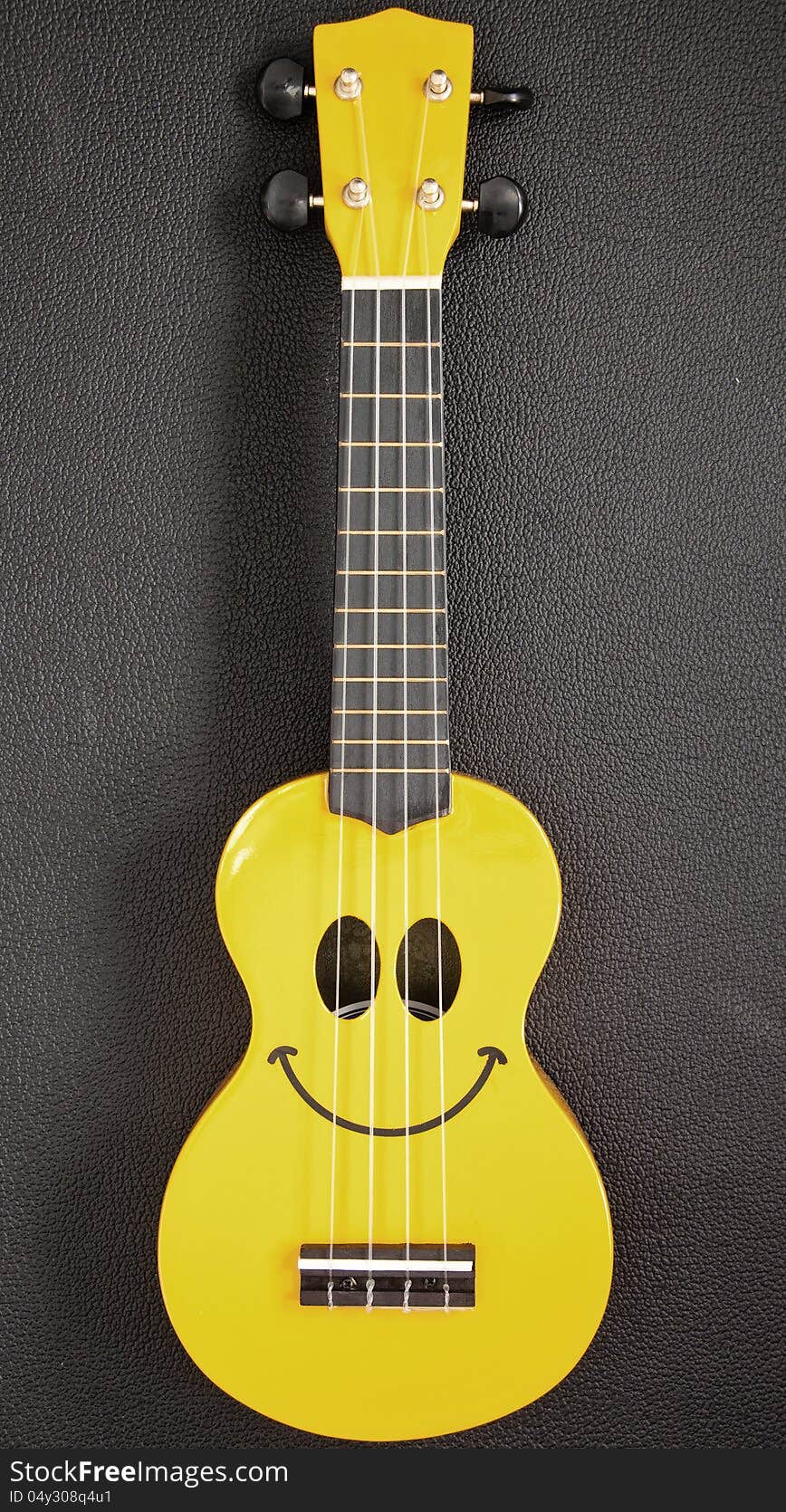 A yellow Ukulele with a smiley face. A yellow Ukulele with a smiley face