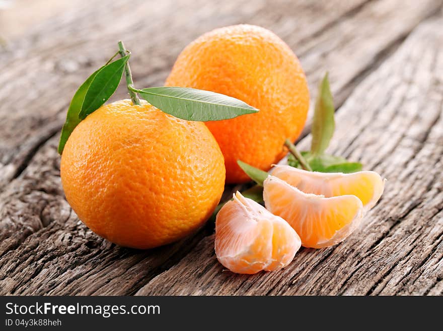 Tangerines with leaves on a wooden table.