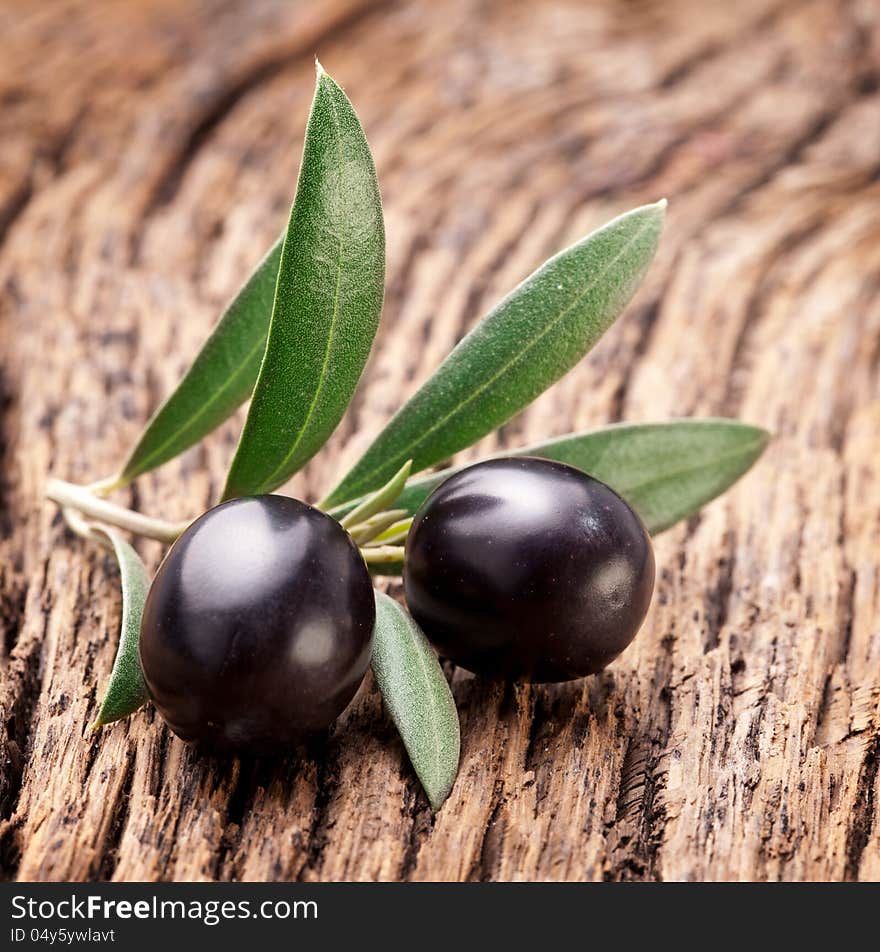 Ripe black olives with leaves on a wooden background. Ripe black olives with leaves on a wooden background.