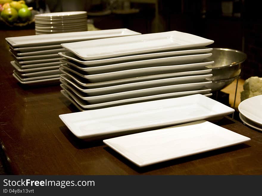 Lots of big plates stack up in a restaurant to for the coming dinner time. Lots of big plates stack up in a restaurant to for the coming dinner time.