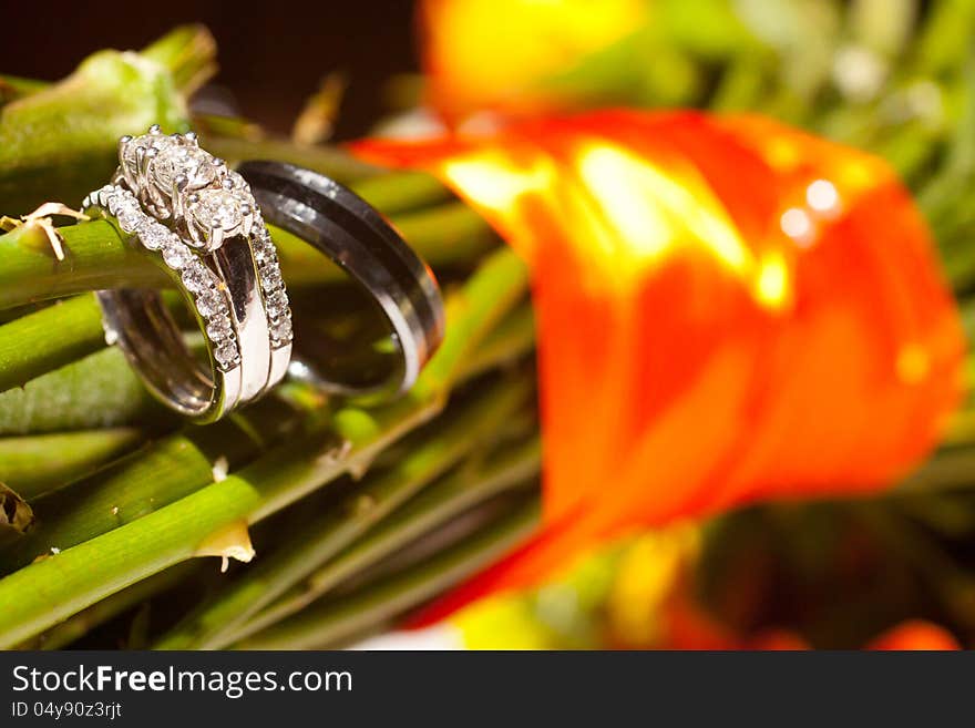 A bride and groom's wedding rings are placed on a bouquet at a ceremony. A bride and groom's wedding rings are placed on a bouquet at a ceremony.