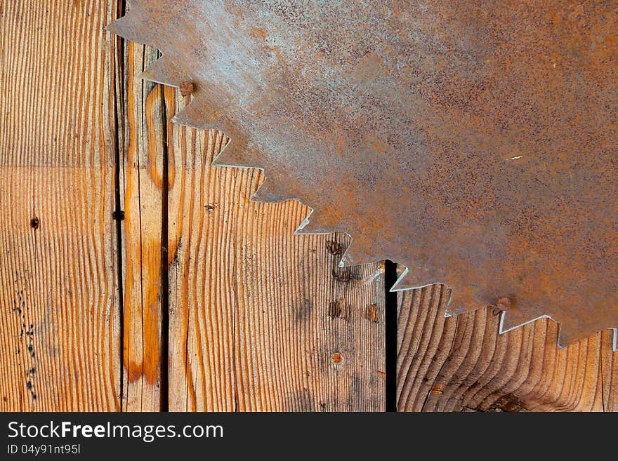 A rusty saw blade is hung on a wood wall to create an interesting and unique abstract background image with plenty of copy space for design. A rusty saw blade is hung on a wood wall to create an interesting and unique abstract background image with plenty of copy space for design.