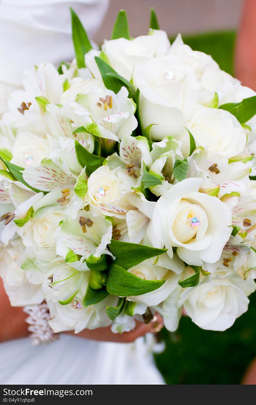 A bride holds her bouquet of flowers at a wedding ceremony while wearing a white dress. A bride holds her bouquet of flowers at a wedding ceremony while wearing a white dress.