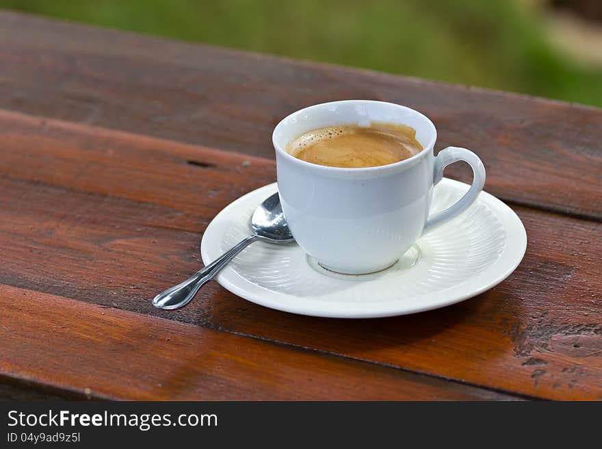 Coffee in a white mug on a wooden table in the garden.