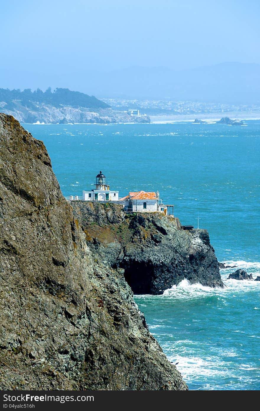 Lighthouse on the cliff and city in the fog on the background in California, USA. Lighthouse on the cliff and city in the fog on the background in California, USA