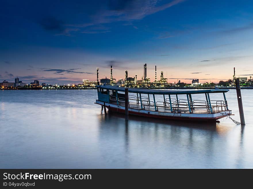 Boat With Oil Refinery At Twilight