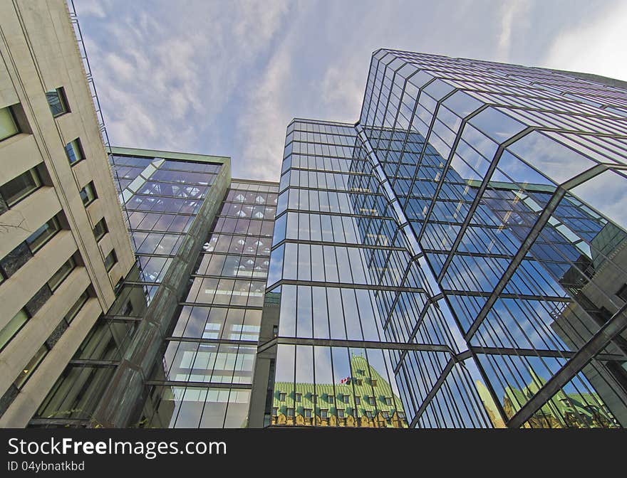 West Wing of Parliament Buildings reflected in glass of modern building in Ottawa, Canada