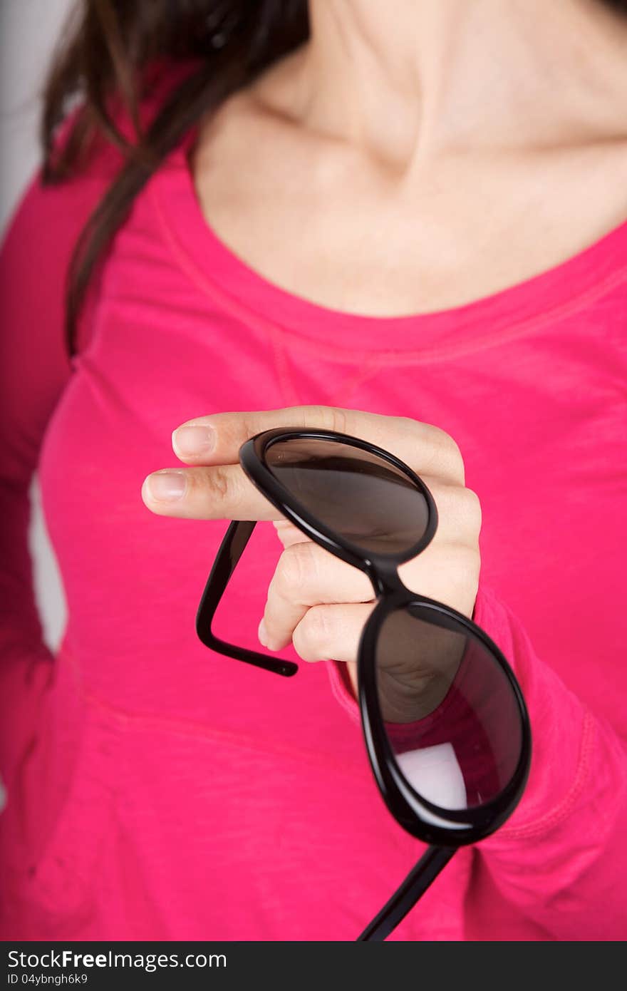 Woman pink shirt detail holding a black sunglasses. Woman pink shirt detail holding a black sunglasses